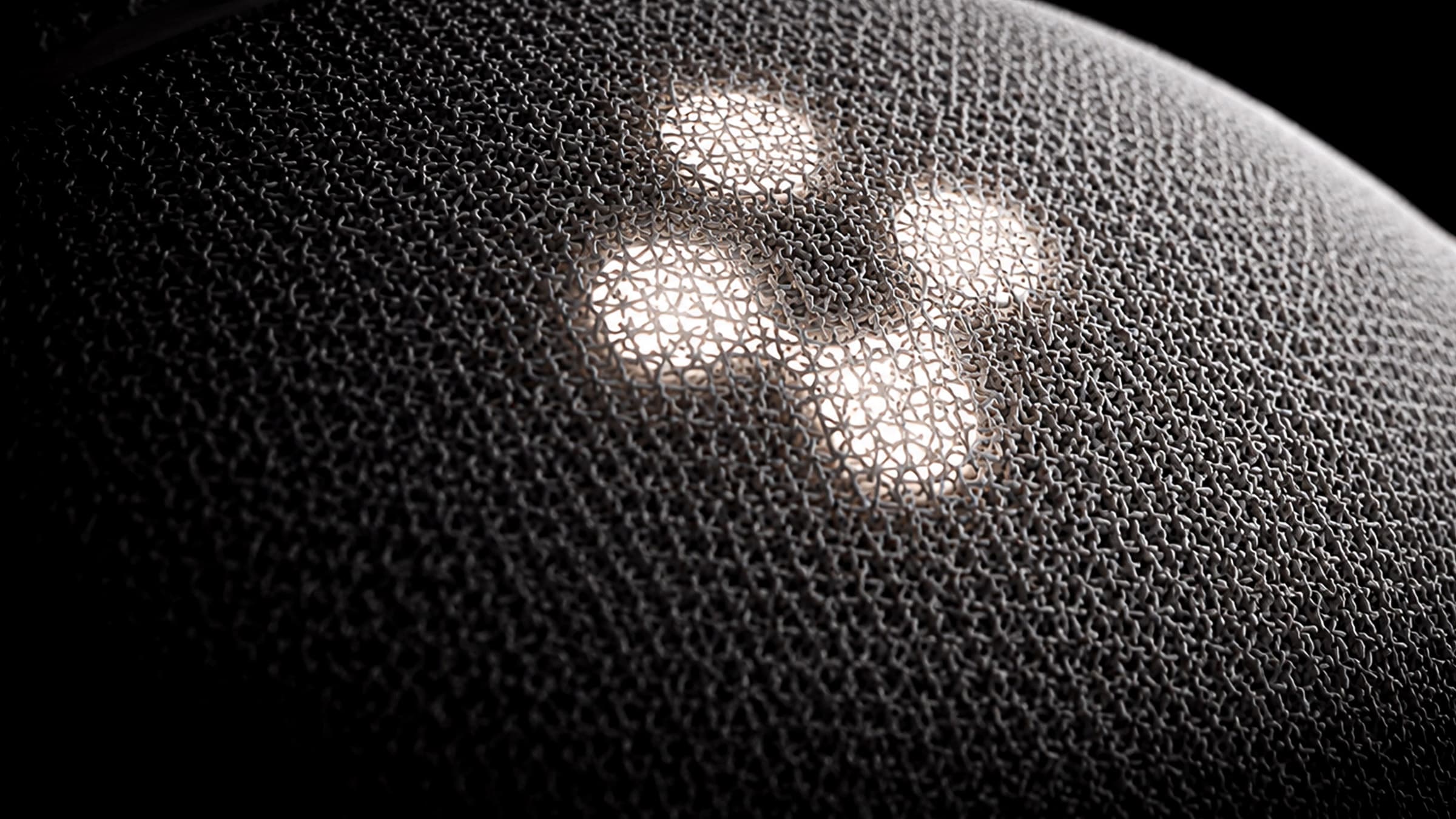 Robot umanoide A1: macro della maglia tecnica con il logo a tre lobi illuminato di luce calda.
